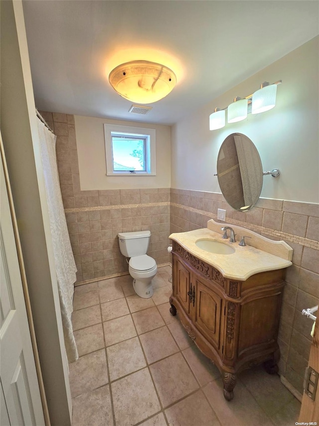 bathroom with tile patterned floors, vanity, toilet, and tile walls