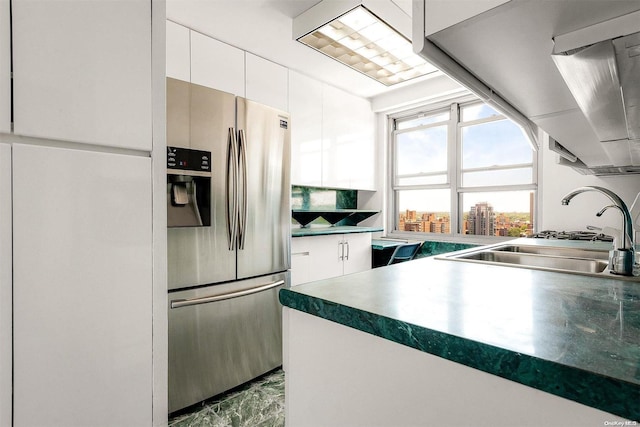 kitchen with stainless steel fridge, sink, and white cabinets