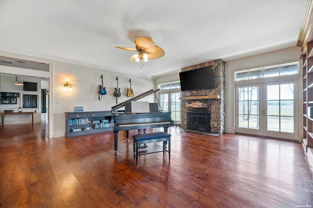 misc room with ceiling fan, wood-type flooring, a fireplace, and a wealth of natural light