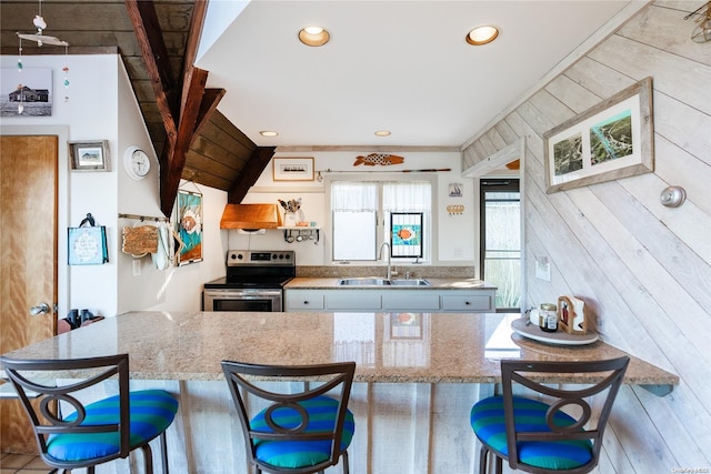 kitchen with a kitchen bar, stainless steel electric range oven, sink, and light stone countertops