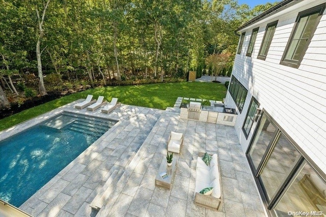 view of swimming pool with a yard, a patio, and an outdoor kitchen