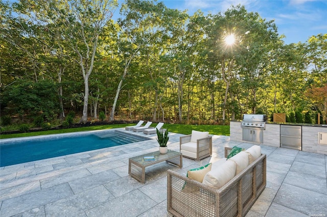 view of swimming pool with outdoor lounge area, an outdoor kitchen, area for grilling, and a patio area