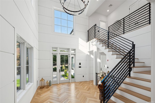 foyer entrance with a towering ceiling, a wealth of natural light, and light parquet floors