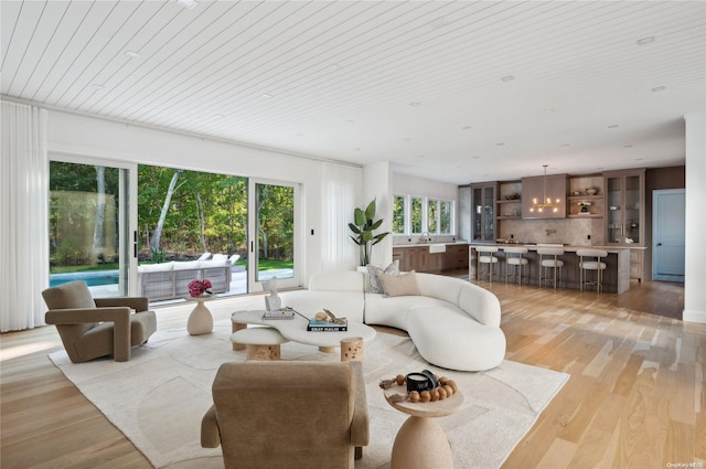 living room featuring wood ceiling, light hardwood / wood-style floors, and indoor bar