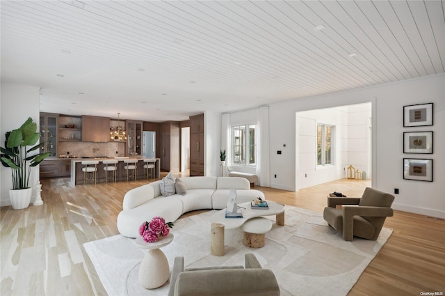 living room with a chandelier, light hardwood / wood-style flooring, and wood ceiling