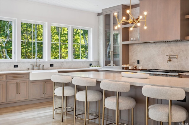 kitchen featuring a breakfast bar, sink, hanging light fixtures, and light hardwood / wood-style floors