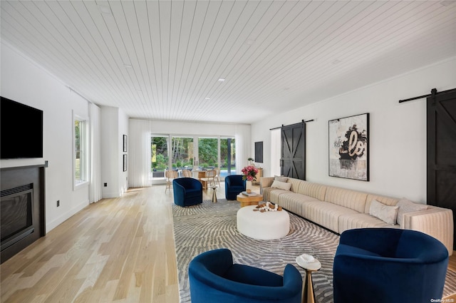 living room with a barn door, light hardwood / wood-style flooring, and wooden ceiling