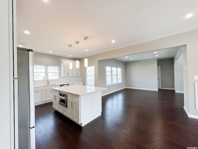 kitchen with appliances with stainless steel finishes, decorative light fixtures, a center island, white cabinetry, and plenty of natural light