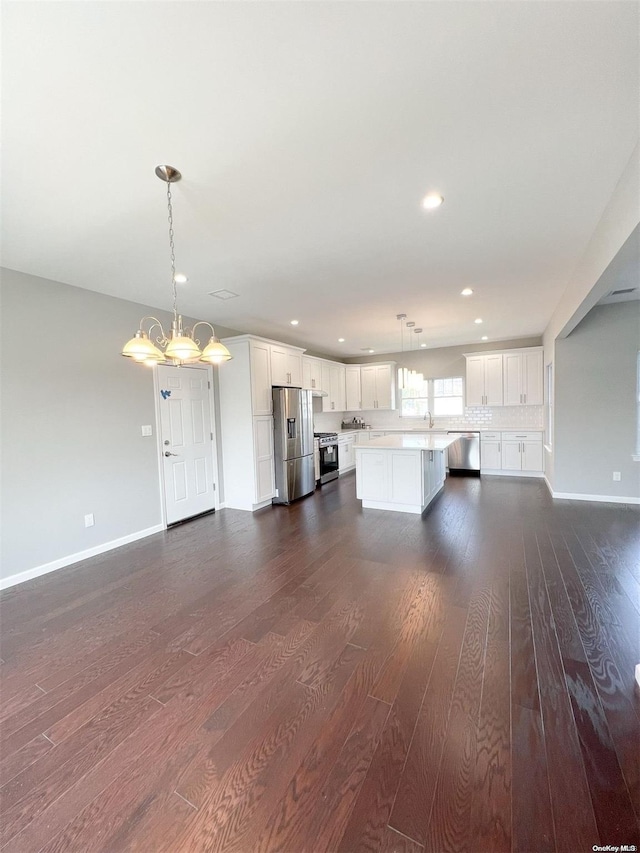 kitchen featuring pendant lighting, a center island, dark hardwood / wood-style floors, appliances with stainless steel finishes, and white cabinetry