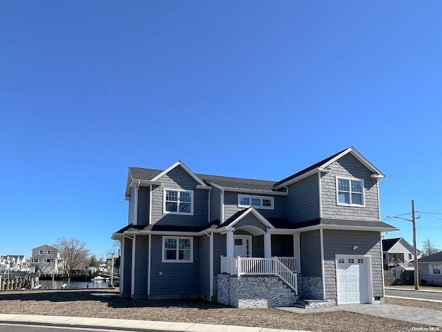 view of front facade with a porch, a garage, and a water view