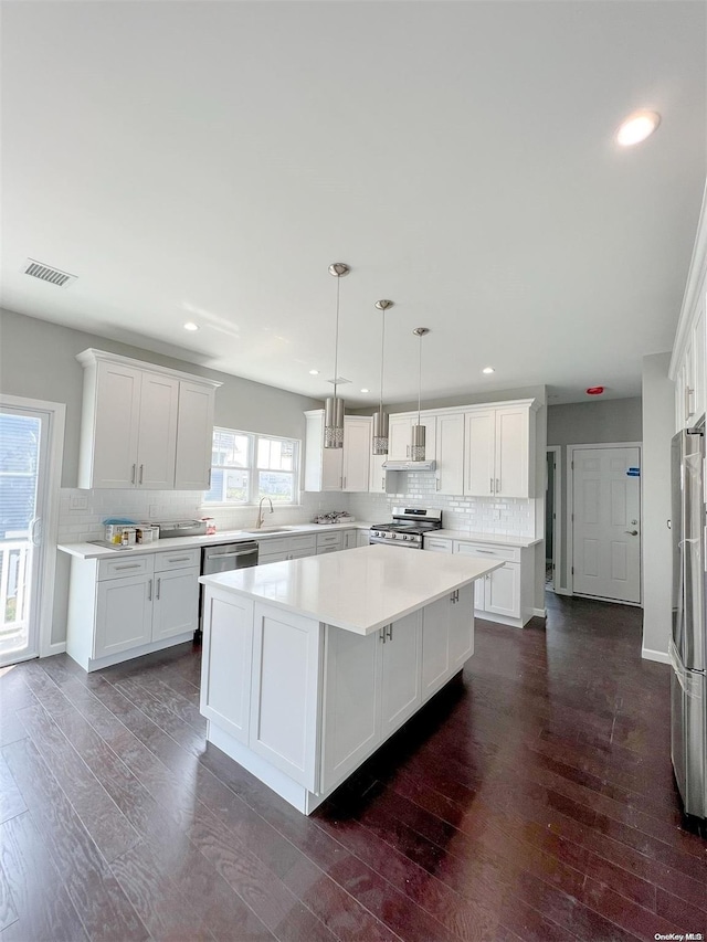 kitchen featuring a center island, dark hardwood / wood-style flooring, white cabinets, and appliances with stainless steel finishes