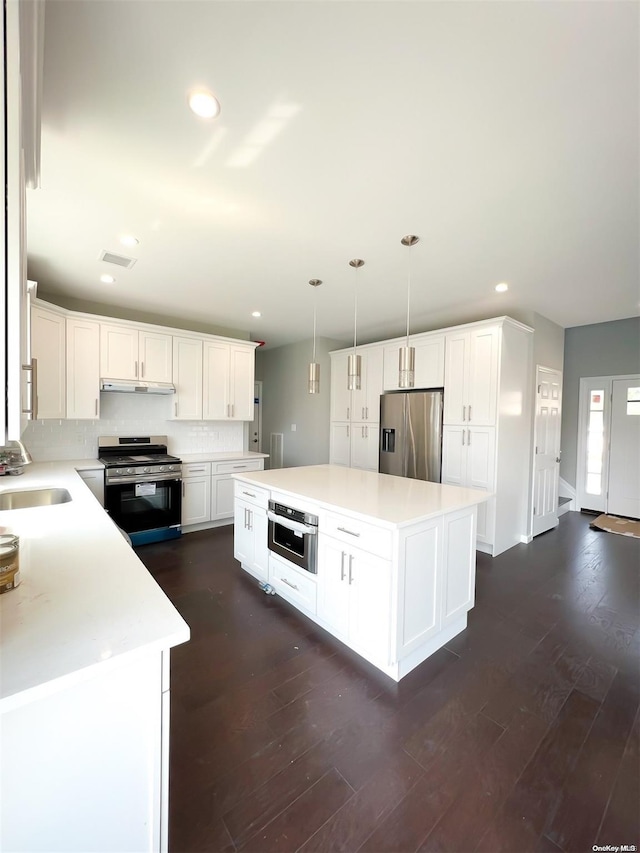 kitchen featuring appliances with stainless steel finishes, a center island, hanging light fixtures, and sink