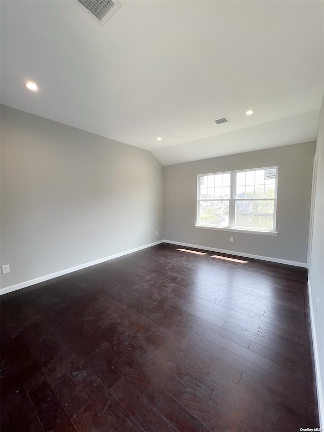 spare room with dark wood-type flooring and vaulted ceiling