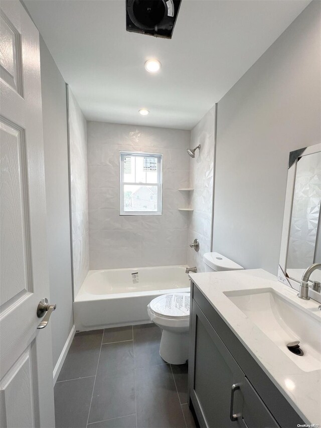 full bathroom featuring tile patterned floors, vanity, toilet, and tiled shower / bath combo