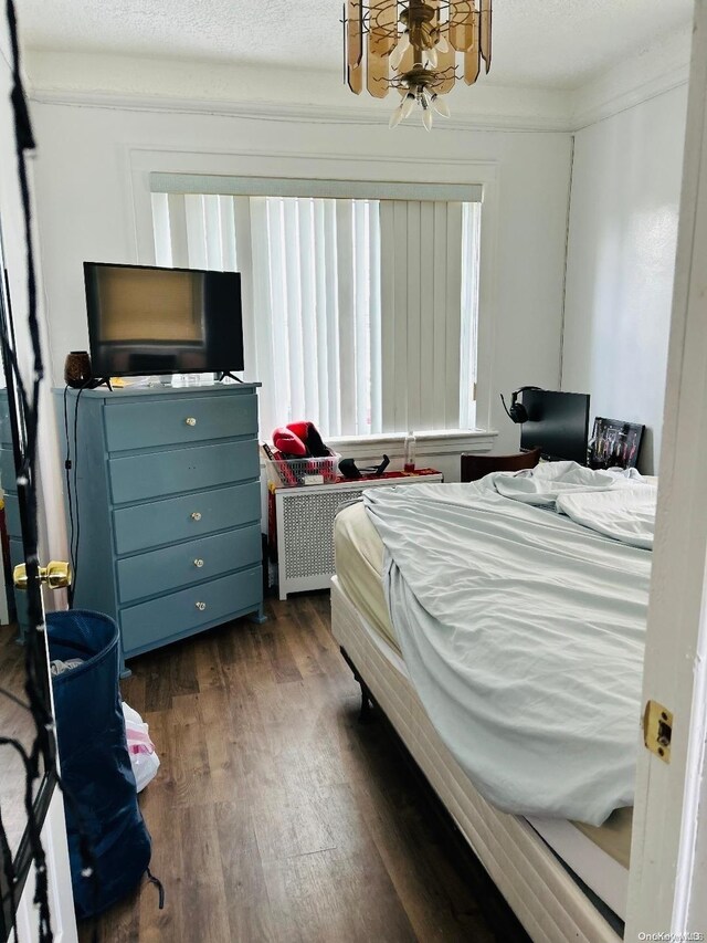 bedroom with dark hardwood / wood-style flooring, a textured ceiling, and ornamental molding