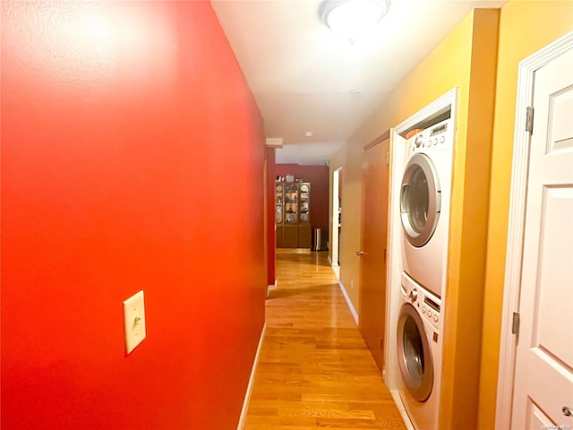 laundry area with stacked washer / drying machine and light wood-type flooring