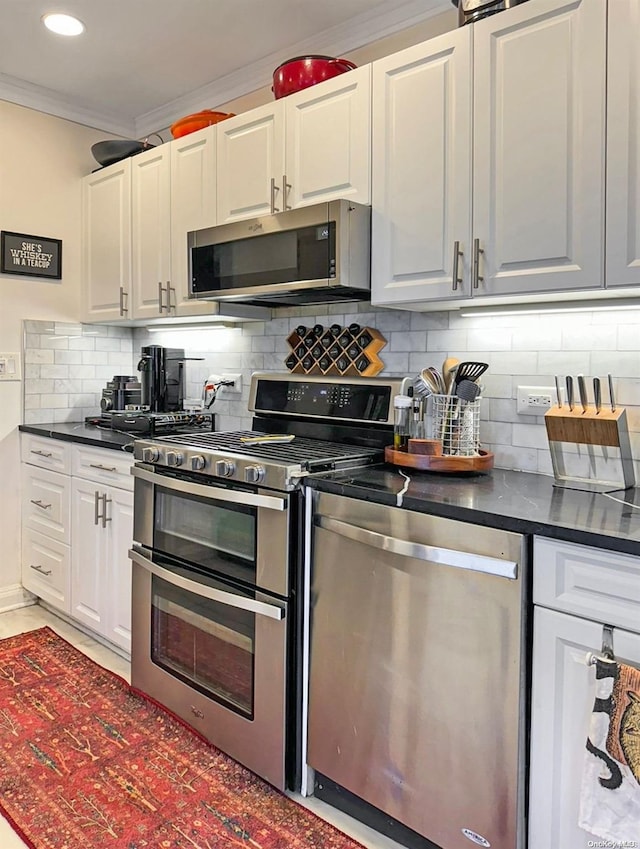 kitchen with white cabinets, decorative backsplash, crown molding, and appliances with stainless steel finishes