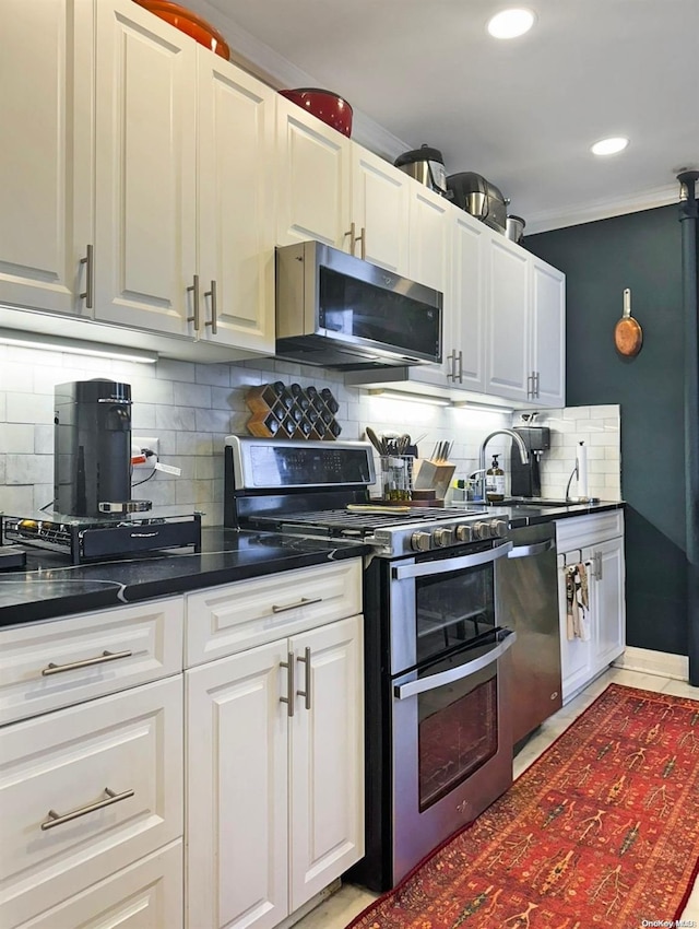 kitchen featuring sink, crown molding, decorative backsplash, white cabinetry, and stainless steel appliances