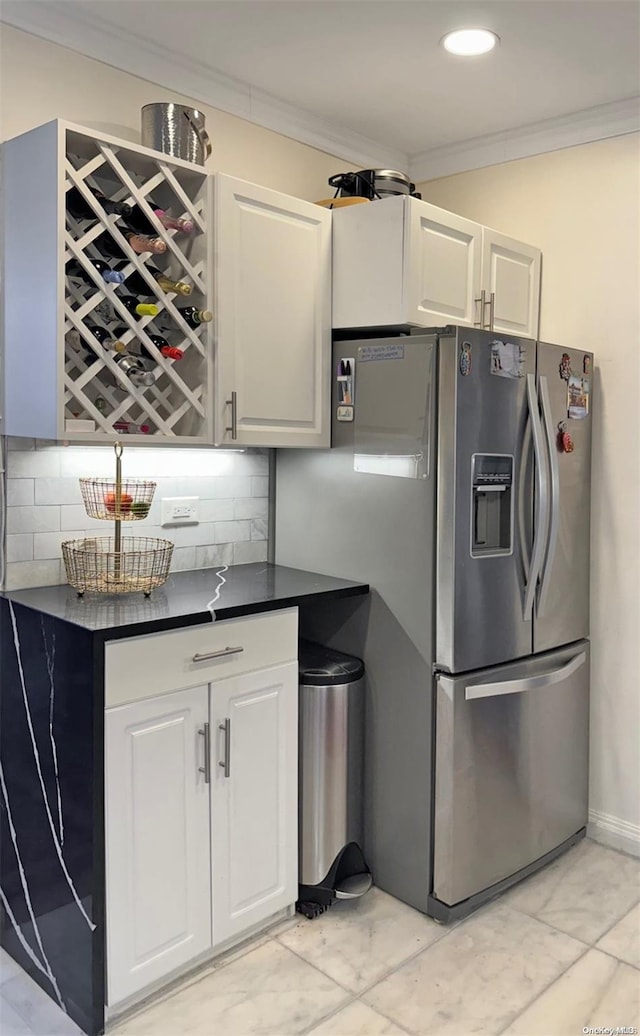 kitchen with white cabinetry, decorative backsplash, and stainless steel fridge