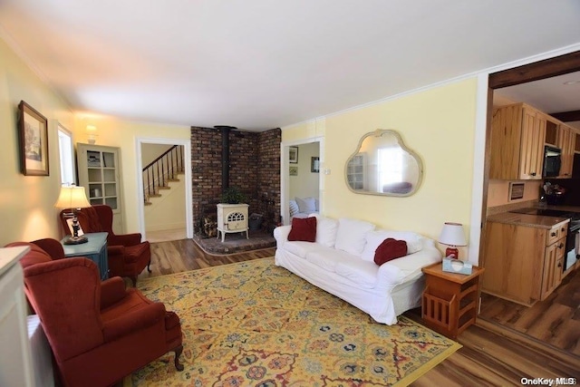 living room featuring a wood stove, crown molding, and dark wood-type flooring