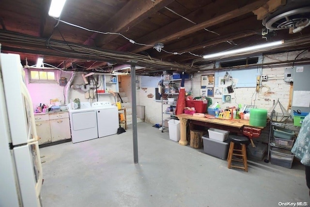 basement with a workshop area, white refrigerator, and independent washer and dryer