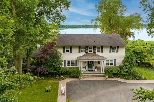 colonial inspired home with covered porch and a water view