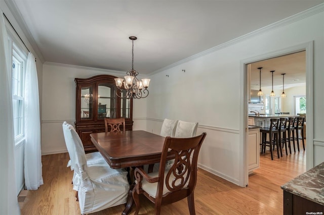 dining room featuring a notable chandelier, light hardwood / wood-style floors, and crown molding