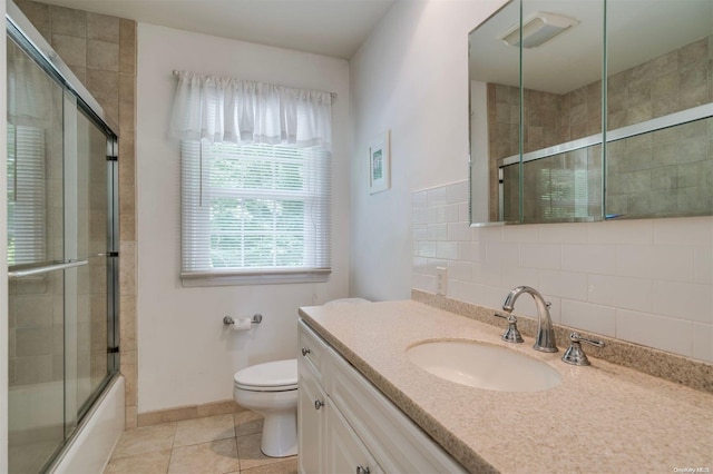 full bathroom featuring tasteful backsplash, tile patterned flooring, bath / shower combo with glass door, toilet, and vanity