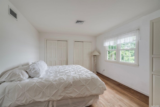 bedroom with multiple closets and light wood-type flooring