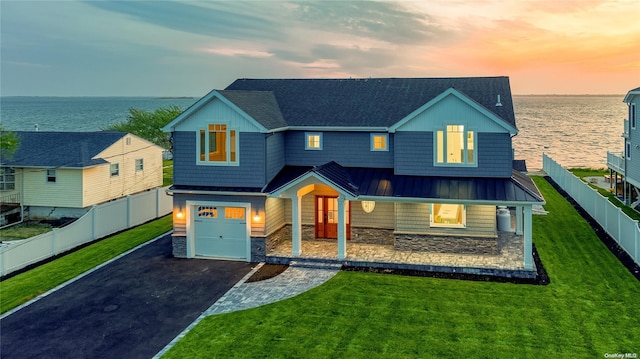 view of front of house featuring a yard, a water view, and a garage