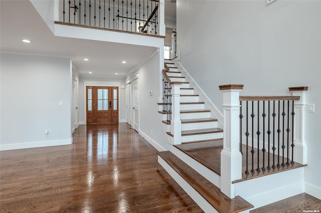 staircase featuring crown molding, a towering ceiling, and wood-type flooring