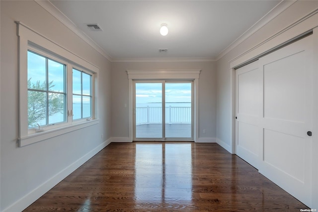 unfurnished bedroom with ornamental molding, a closet, multiple windows, and dark wood-type flooring