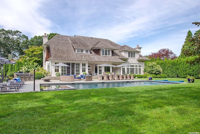 back of property featuring outdoor lounge area, a patio area, and a lawn