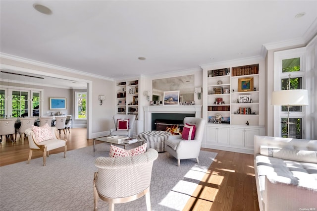 living room featuring built in shelves, crown molding, and dark wood-type flooring