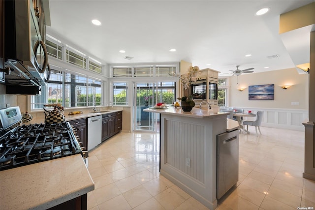 kitchen featuring a center island with sink, plenty of natural light, stainless steel appliances, and ceiling fan