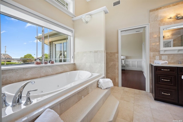 bathroom featuring tile patterned floors, vanity, and a relaxing tiled tub