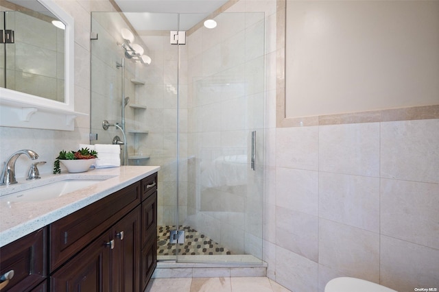 bathroom featuring walk in shower, vanity, and tile walls