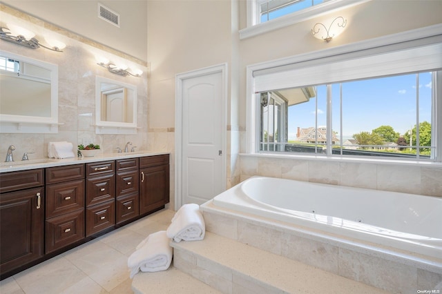 bathroom with tile patterned floors, tiled bath, and vanity