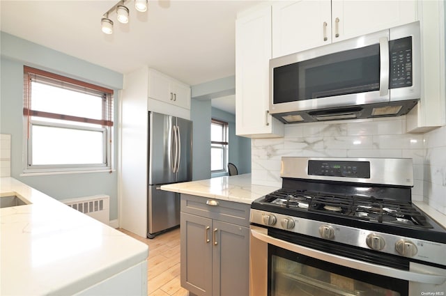 kitchen with a healthy amount of sunlight, decorative backsplash, white cabinetry, and stainless steel appliances