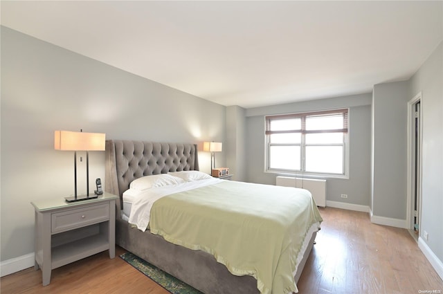 bedroom with radiator heating unit and light wood-type flooring