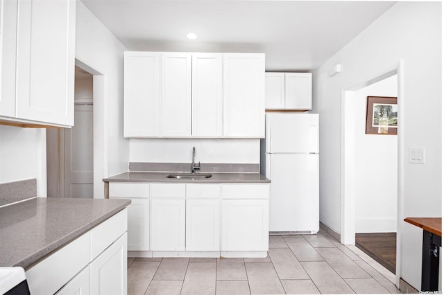 kitchen featuring white cabinetry, sink, white fridge, and light tile patterned floors