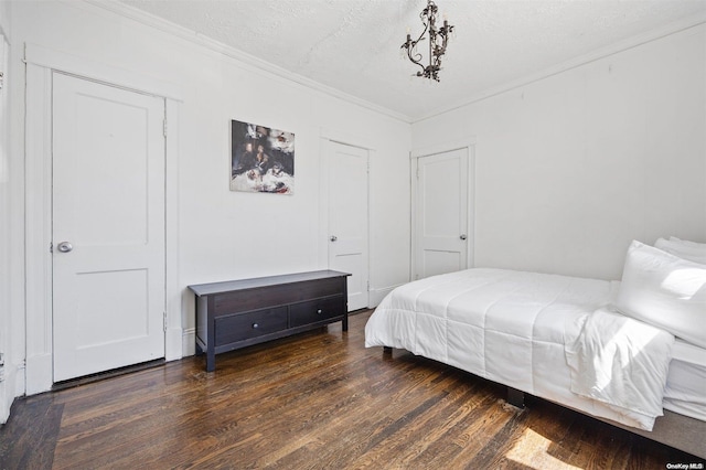 bedroom featuring crown molding, dark wood-type flooring, and a textured ceiling