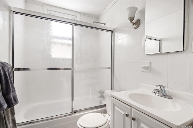 full bathroom featuring vanity, shower / bath combination with glass door, toilet, tile walls, and tasteful backsplash