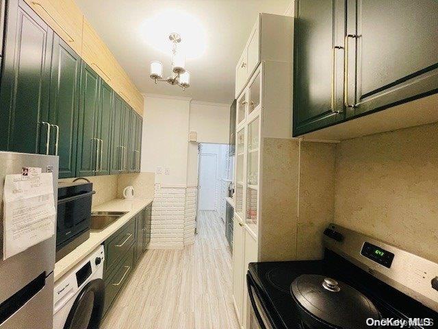 washroom featuring a notable chandelier, washer / dryer, sink, and light hardwood / wood-style flooring