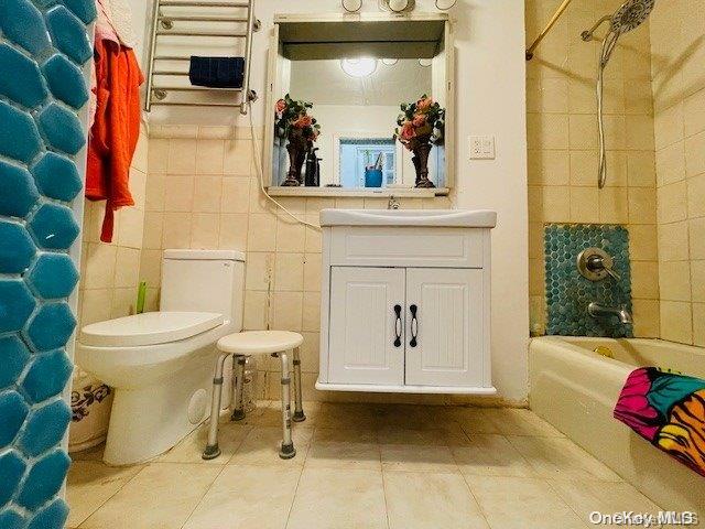 full bathroom with vanity, tile patterned flooring, toilet, tile walls, and shower / tub combo