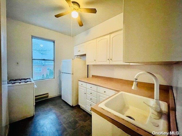 kitchen with white appliances, white cabinetry, ceiling fan, and sink