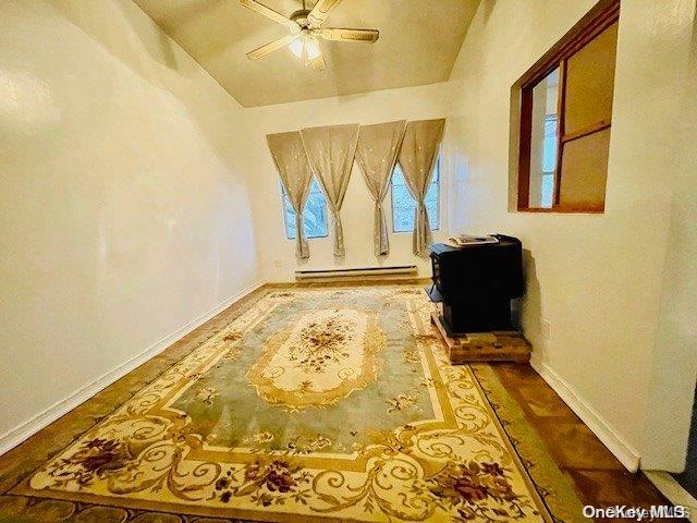 interior space featuring ceiling fan, vaulted ceiling, and a baseboard heating unit