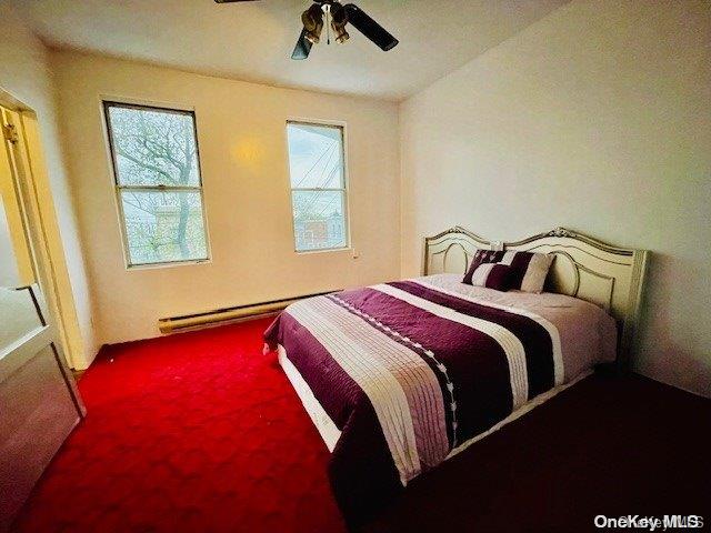 carpeted bedroom featuring ceiling fan, a baseboard radiator, and multiple windows