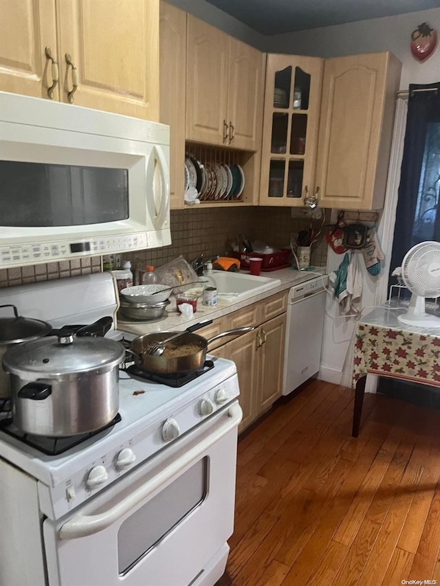 kitchen featuring decorative backsplash, white appliances, sink, wood-type flooring, and light brown cabinets