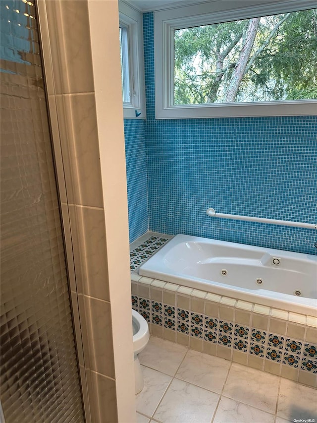 bathroom featuring tiled tub and toilet